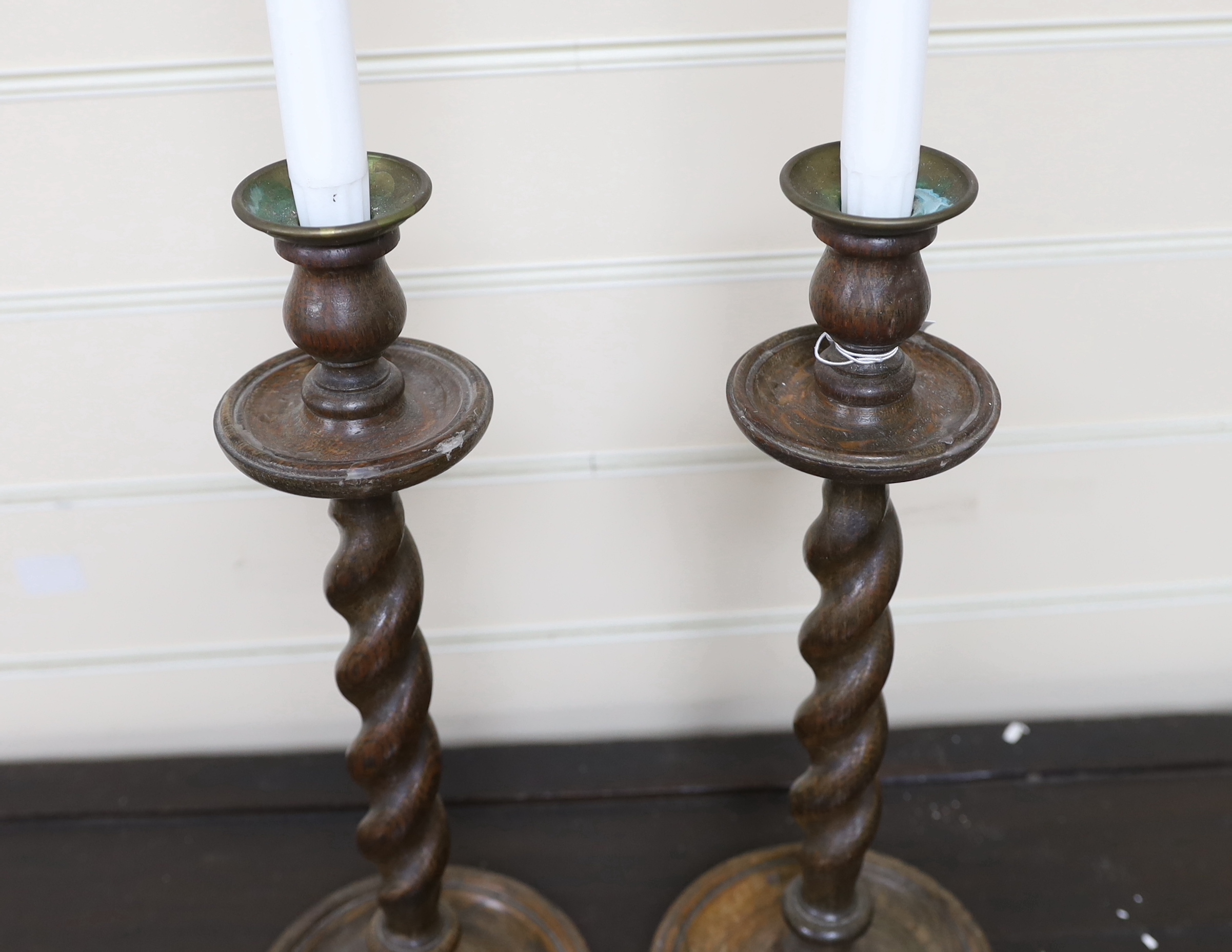 A pair of early 20th century spiral turned candlesticks with brass sconces, height 38cm